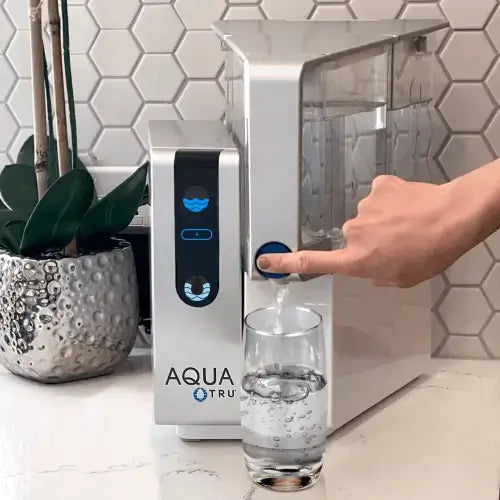 AquaTru Classic Countertop Water Purifier dispensing clean water into a glass on a kitchen counter.