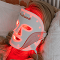 Woman using Infraredi LED Red Light Therapy Mask for skincare treatment.