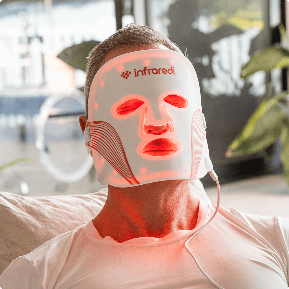 Man using Infraredi LED red light therapy mask for skin rejuvenation at home.