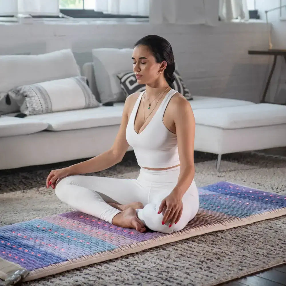 Woman meditating on Healthyline Rainbow Chakra PEMF Mat™ 7428 for spiritual balance and recovery.