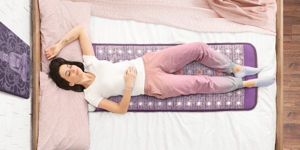 Woman relaxing on Sparkle Mats Infrared PEMF Mat for stress relief and warmth.