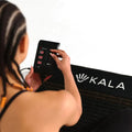 Person adjusting settings on Kala Infrared PEMF Mat, designed for advanced healing and pain relief in Canada, 2024.