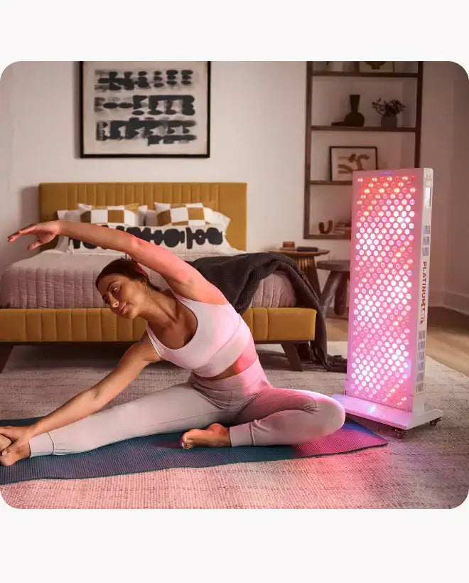 Woman using Platinum LED Biomax 900 for full body red light therapy in her living room.