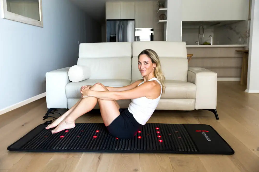 Woman using Bon Charge Infrared PEMF Mat Max at home for therapy and relaxation.